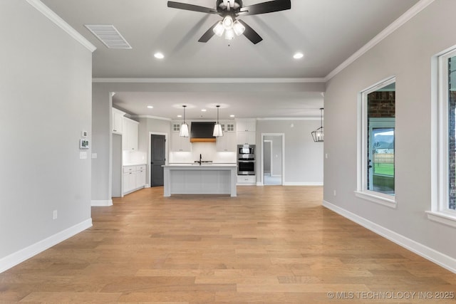 unfurnished living room with visible vents, ornamental molding, baseboards, and ceiling fan
