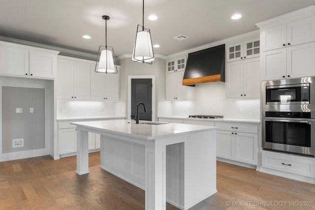 kitchen featuring visible vents, tasteful backsplash, a sink, light countertops, and custom exhaust hood