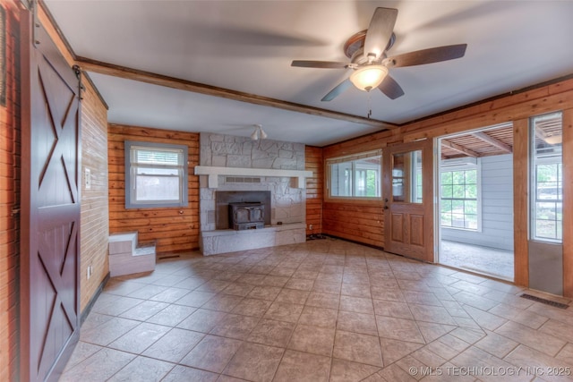 16703 Grisham Ave, Sapulpa, OK 74066 - unfurnished living room with wooden walls, ceiling fan, beam ceiling, and a wood stove