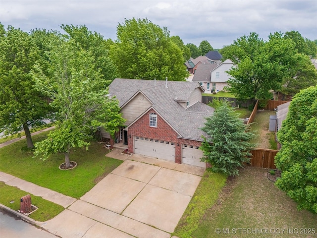 view of front of house featuring driveway, a garage, brick siding, fence, and a front lawn