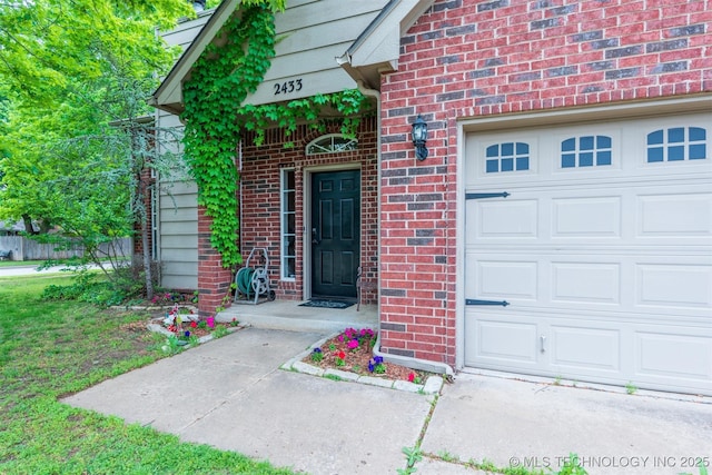 doorway to property with an attached garage and brick siding