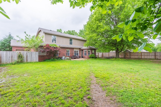 rear view of house with a lawn, brick siding, and a fenced backyard