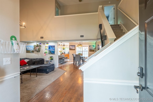staircase with a notable chandelier, a high ceiling, visible vents, and wood finished floors