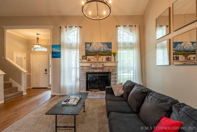 living room with plenty of natural light, a stone fireplace, wood finished floors, and stairway