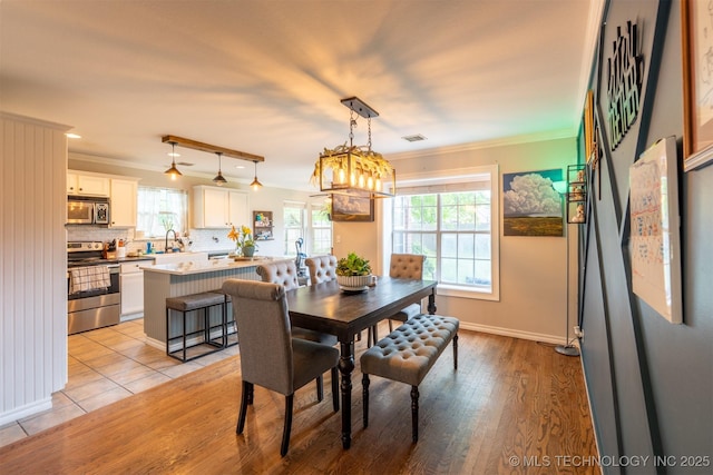dining space with baseboards, ornamental molding, and light wood-type flooring