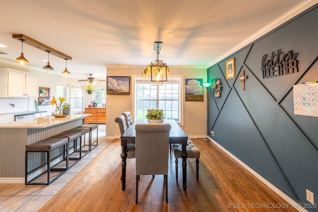 dining room featuring crown molding, baseboards, and light wood-style floors