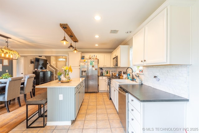 kitchen featuring ornamental molding, a center island, white cabinetry, tasteful backsplash, and appliances with stainless steel finishes