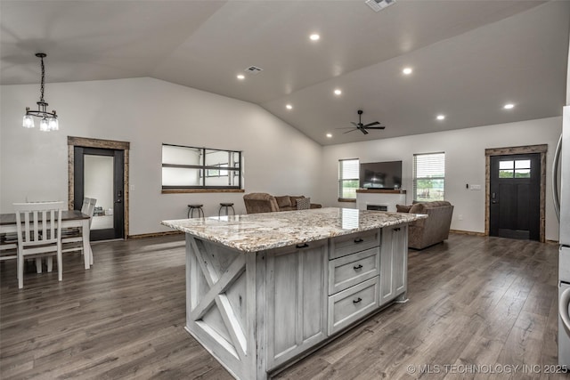 kitchen with dark wood-style flooring, ceiling fan with notable chandelier, vaulted ceiling, a kitchen island, and gray cabinetry