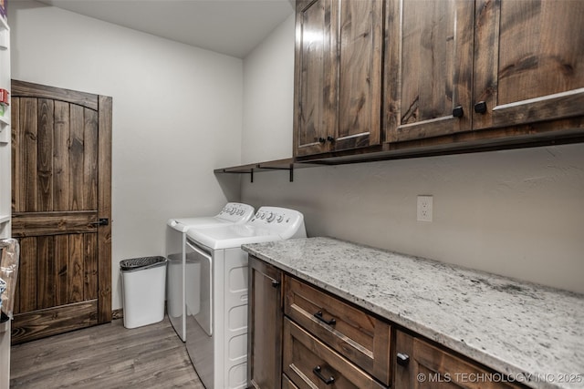 laundry room with separate washer and dryer, light wood-type flooring, and cabinet space