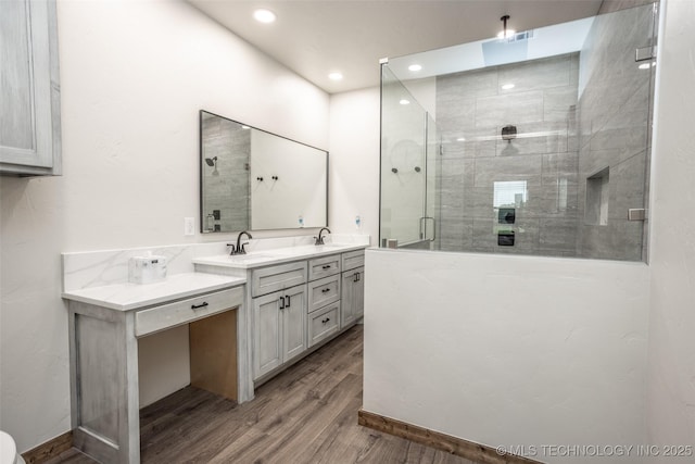bathroom featuring a sink, double vanity, recessed lighting, a shower stall, and wood finished floors