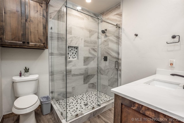 bathroom with vanity, a stall shower, toilet, and wood finished floors