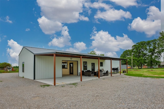 back of property featuring a patio, an outdoor living space, and metal roof