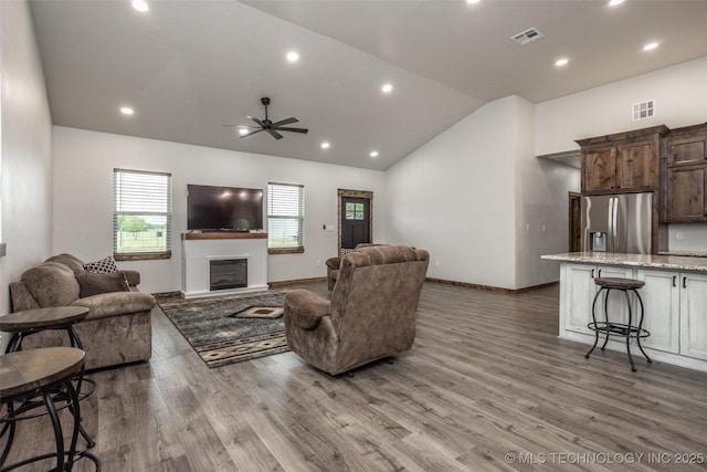 living area featuring visible vents, a wealth of natural light, lofted ceiling, and wood finished floors