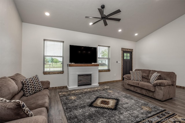 living area with a ceiling fan, a glass covered fireplace, lofted ceiling, and wood finished floors