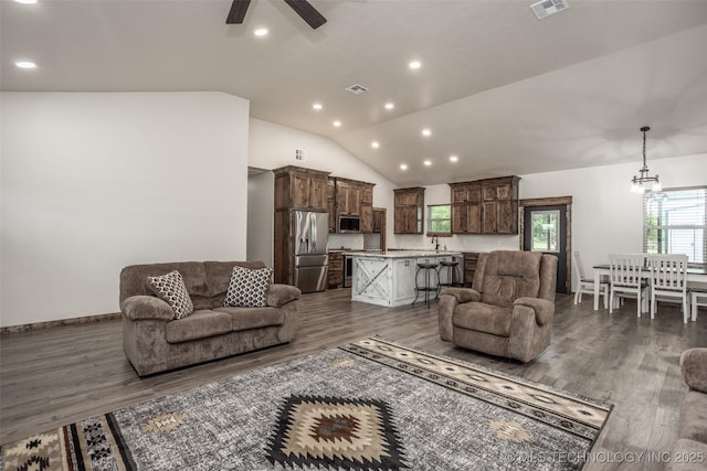 living room with visible vents, ceiling fan with notable chandelier, wood finished floors, and lofted ceiling