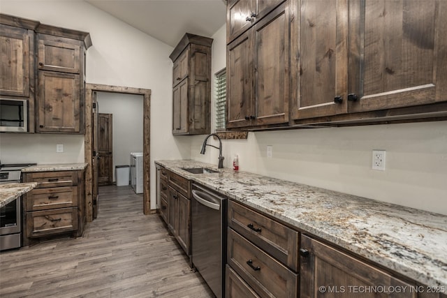 kitchen featuring a sink, appliances with stainless steel finishes, dark brown cabinetry, and vaulted ceiling