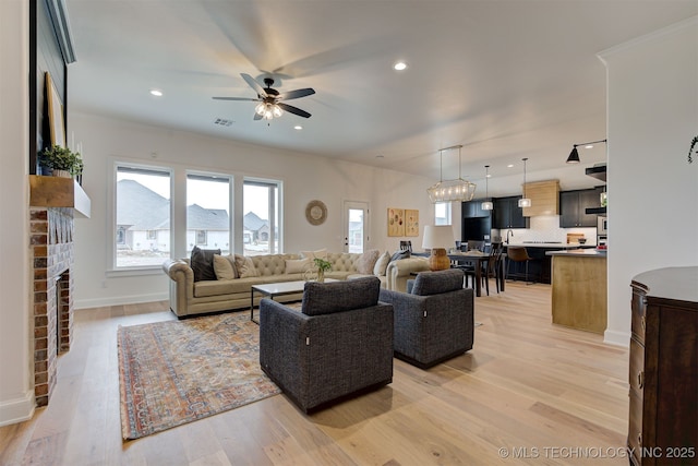 living room featuring a ceiling fan, a fireplace, light wood-type flooring, baseboards, and recessed lighting