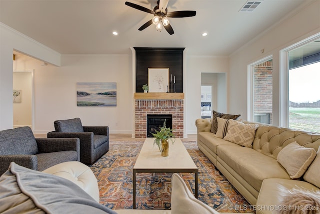 living room with ceiling fan, visible vents, crown molding, a fireplace, and recessed lighting