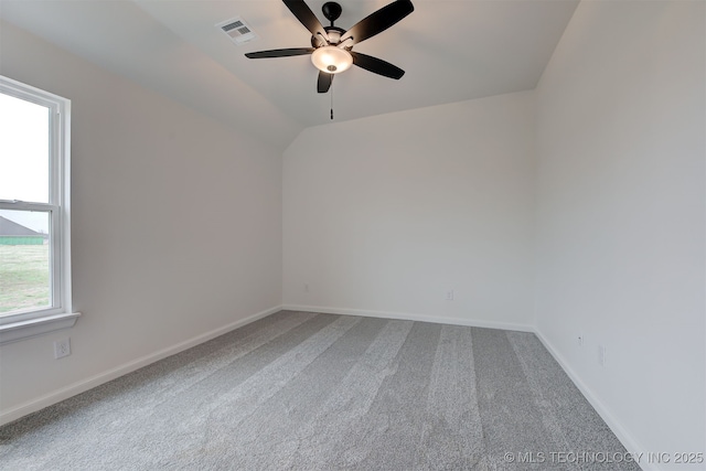carpeted empty room with visible vents, baseboards, ceiling fan, and vaulted ceiling
