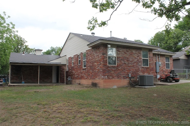 view of side of home featuring a chimney, a yard, central AC, and brick siding