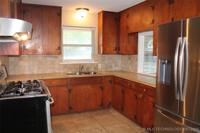 kitchen with decorative backsplash, light countertops, under cabinet range hood, a sink, and stainless steel appliances