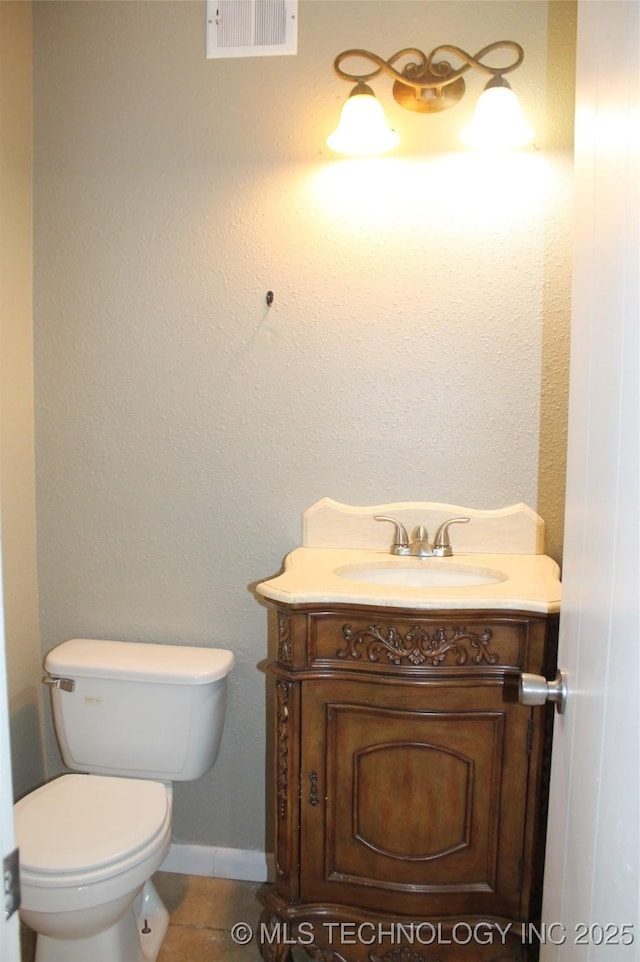 bathroom featuring vanity, toilet, tile patterned floors, baseboards, and visible vents