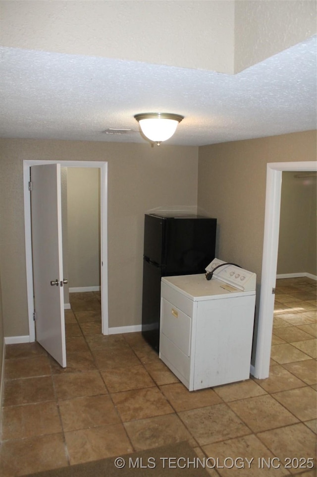 washroom featuring baseboards, a textured ceiling, washer / dryer, and light tile patterned floors