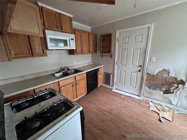 kitchen with crown molding, wood finished floors, white appliances, light countertops, and a sink