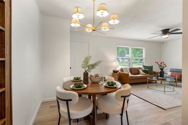 dining area featuring baseboards, light wood-style flooring, and ceiling fan with notable chandelier