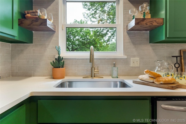 kitchen featuring light countertops, green cabinetry, tasteful backsplash, a sink, and dishwasher