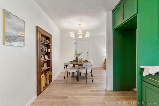 dining room featuring an inviting chandelier, baseboards, and light wood-style flooring