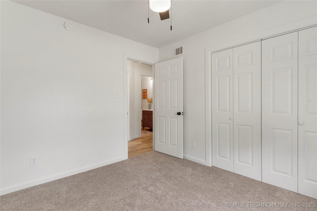 unfurnished bedroom featuring ceiling fan, light carpet, baseboards, visible vents, and a closet
