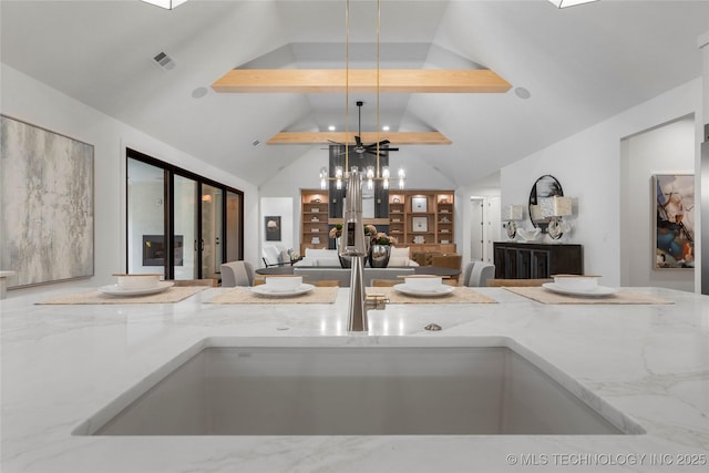 room details with visible vents, hanging light fixtures, light stone countertops, beamed ceiling, and a chandelier