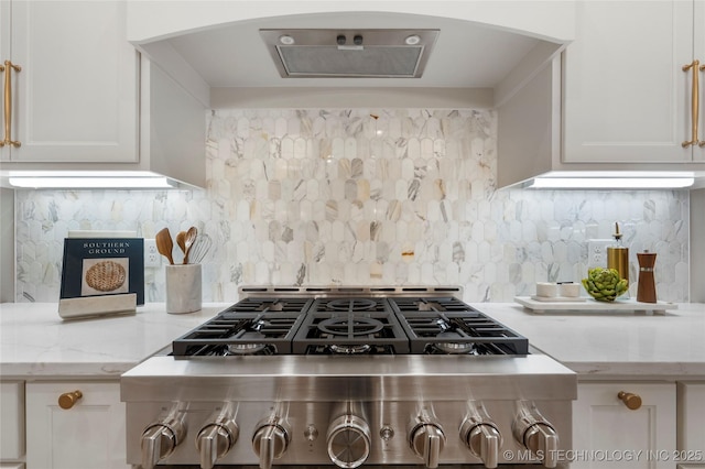 kitchen featuring decorative backsplash, arched walkways, stove, light stone counters, and white cabinetry