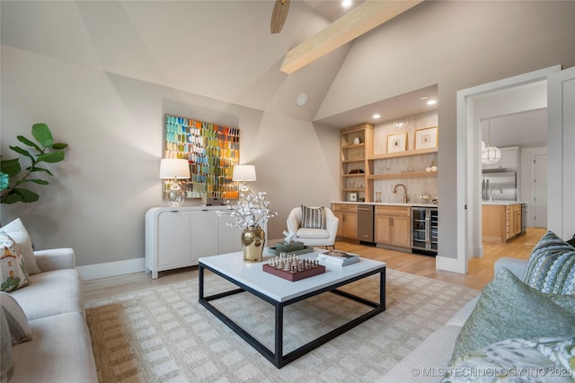 living room with beverage cooler, baseboards, indoor wet bar, high vaulted ceiling, and light wood-type flooring