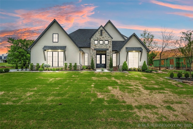 modern farmhouse with french doors, stucco siding, a front lawn, and stone siding