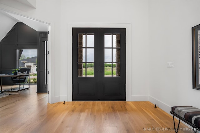 foyer featuring baseboards, french doors, and light wood finished floors