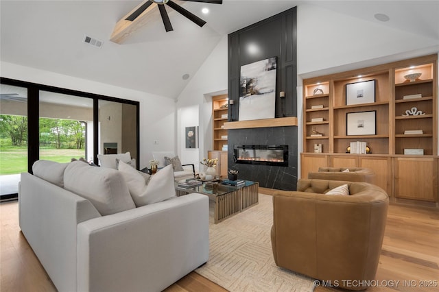 living area featuring a ceiling fan, visible vents, a large fireplace, and light wood finished floors