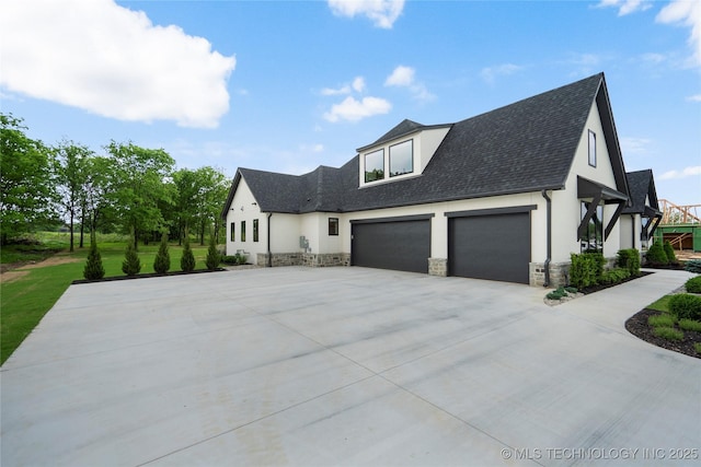 view of home's exterior featuring roof with shingles, stone siding, a garage, stucco siding, and driveway