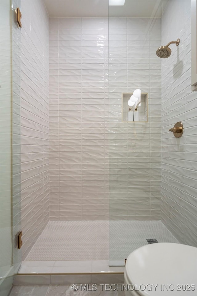 bathroom featuring toilet and a shower stall