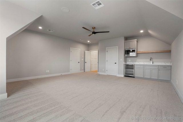 unfurnished living room with wine cooler, baseboards, light carpet, and visible vents