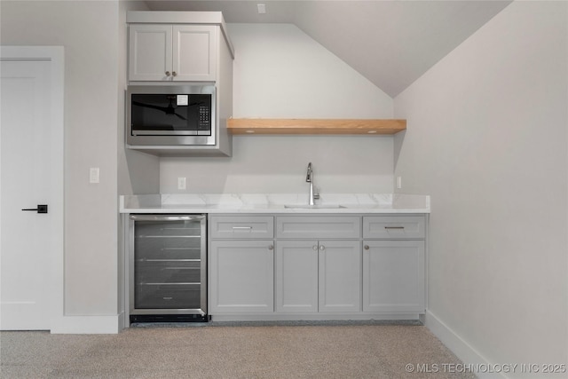 kitchen featuring open shelves, a sink, stainless steel microwave, wine cooler, and light carpet