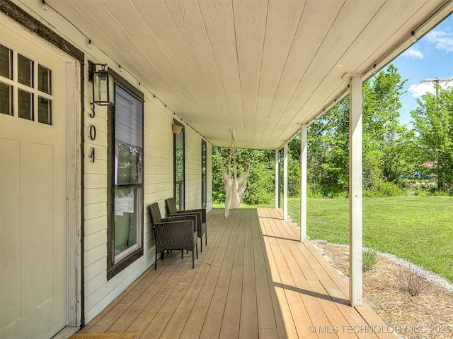 wooden deck featuring a lawn and a porch