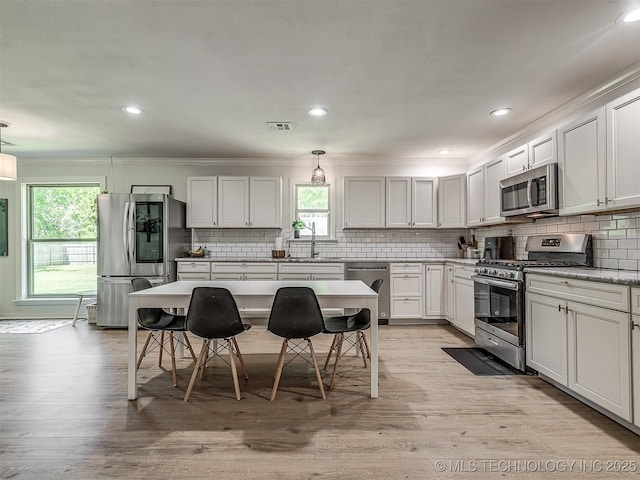 kitchen with backsplash, appliances with stainless steel finishes, plenty of natural light, and a sink