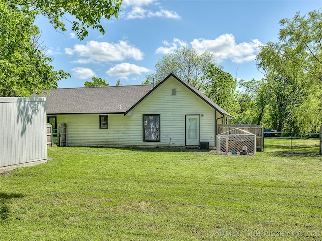 rear view of house with an outbuilding, fence, and a yard