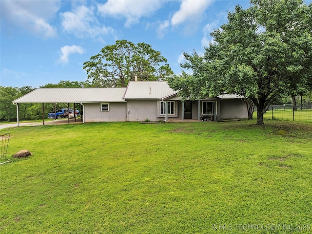 back of house with fence, a yard, an attached carport, and metal roof