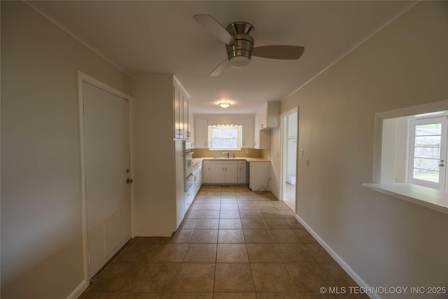 hall featuring a sink, baseboards, tile patterned flooring, and crown molding