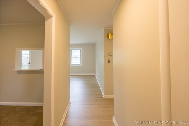 hallway featuring crown molding, baseboards, and wood finished floors