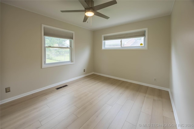 spare room featuring baseboards, visible vents, plenty of natural light, and wood finished floors