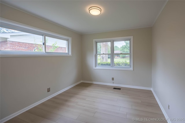 unfurnished room with a healthy amount of sunlight, baseboards, light wood-style floors, and visible vents